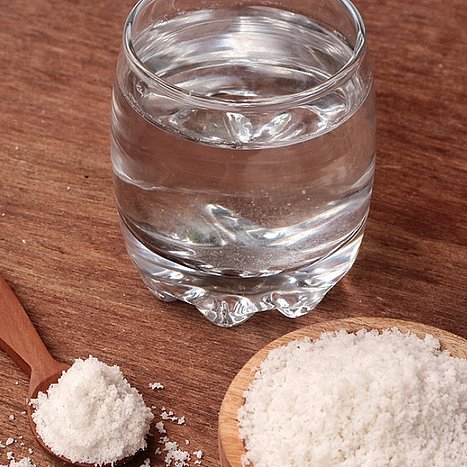 Glas mit Wasser neben Holzschlüssel mit Salz.