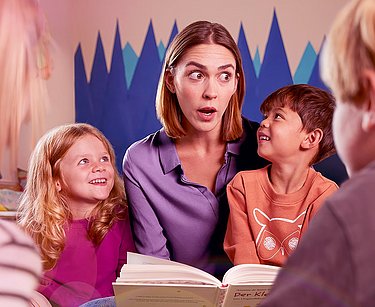 Frau liest Kindern ein Buch vor.