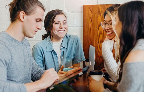 Drei Frauen und ein Mann unterhalten sich und lächeln