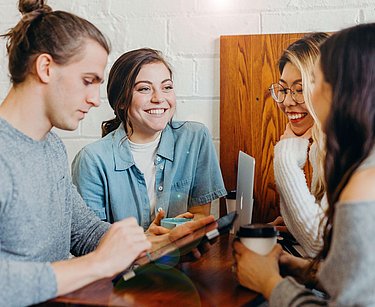 Drei Frauen und ein Mann unterhalten sich und lächeln